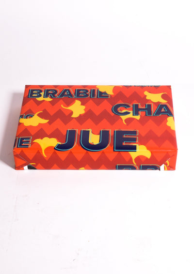 a gift wrapped in a red wrapping paper that says liberian slangs "jue", chamo" brabie"
